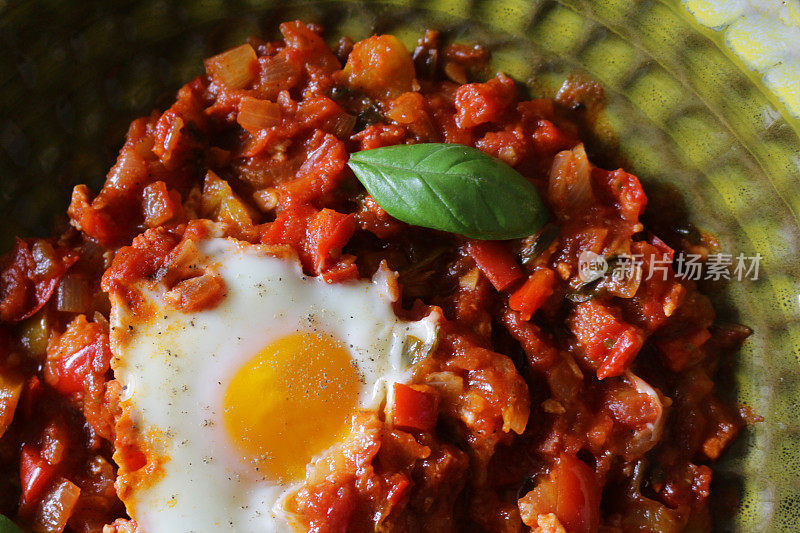 地中海式健康早餐shakshouka / shakshuka / chakchouka在碗里，鸡蛋用西红柿、辣椒、洋葱、橄榄油和大蒜调味。用孜然、红辣椒和胡椒调味的调味汁，配面包片食用。